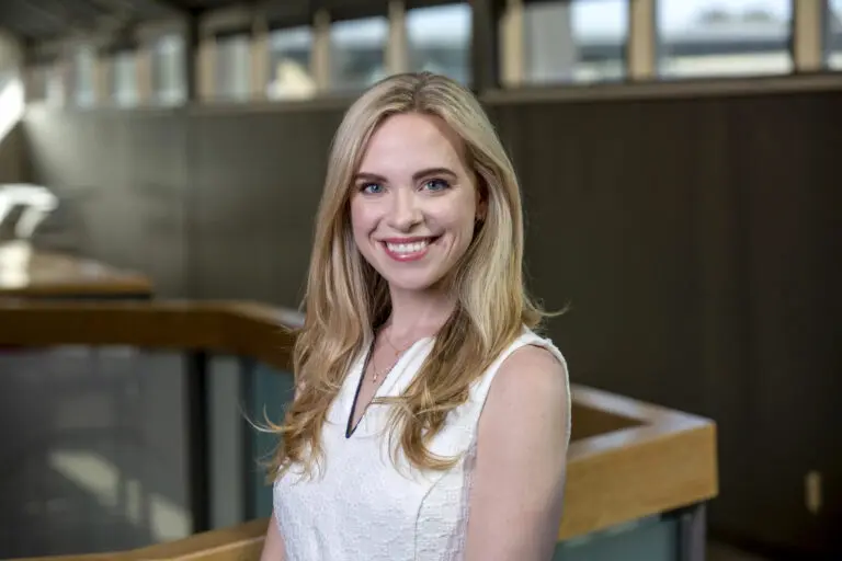 Head shot of a woman in a white blouse in a corporate environment