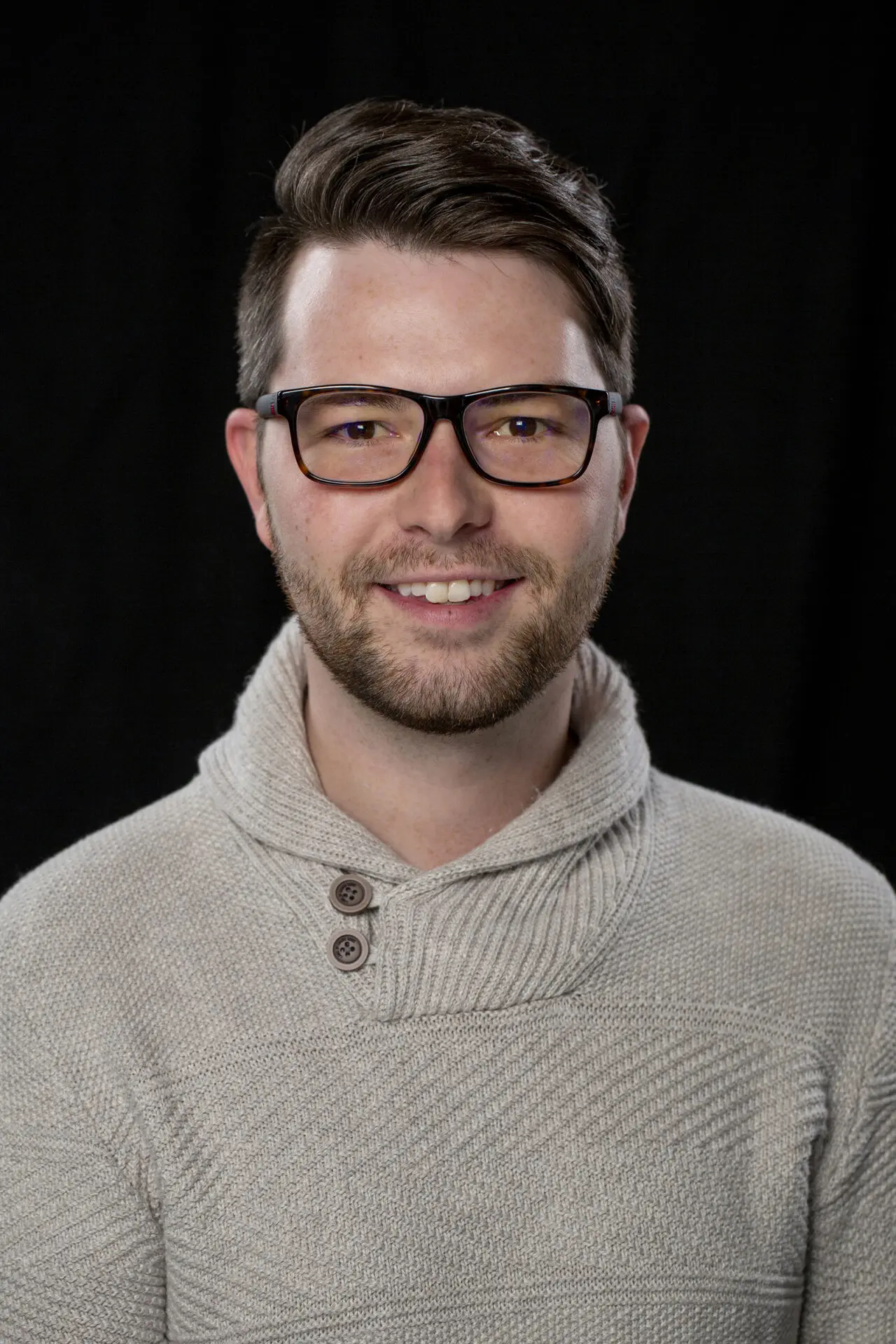 head shot of a man taken in a photography studio on a black background.