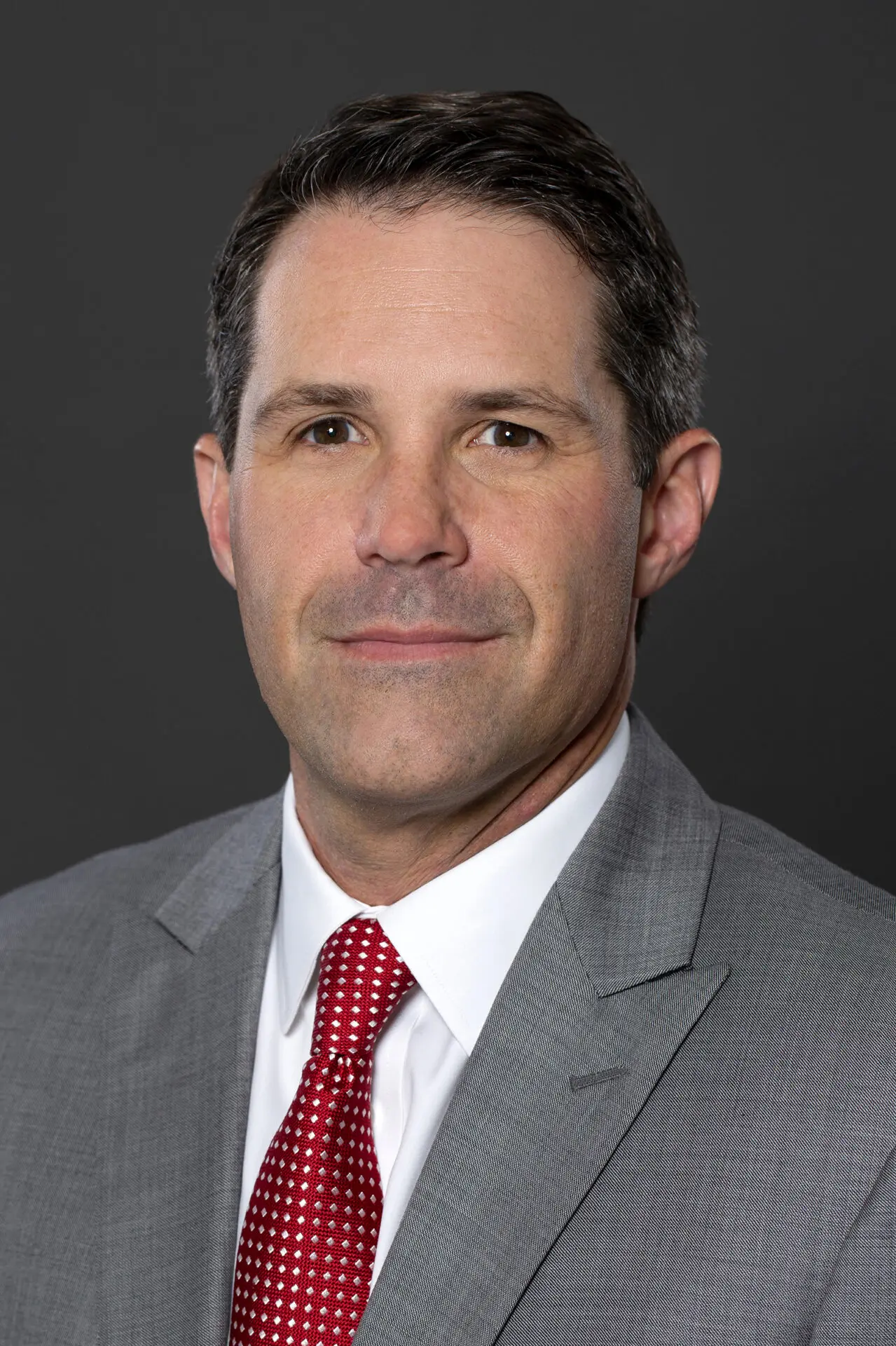 head shot of a man taken in a photography studio on a dark background.