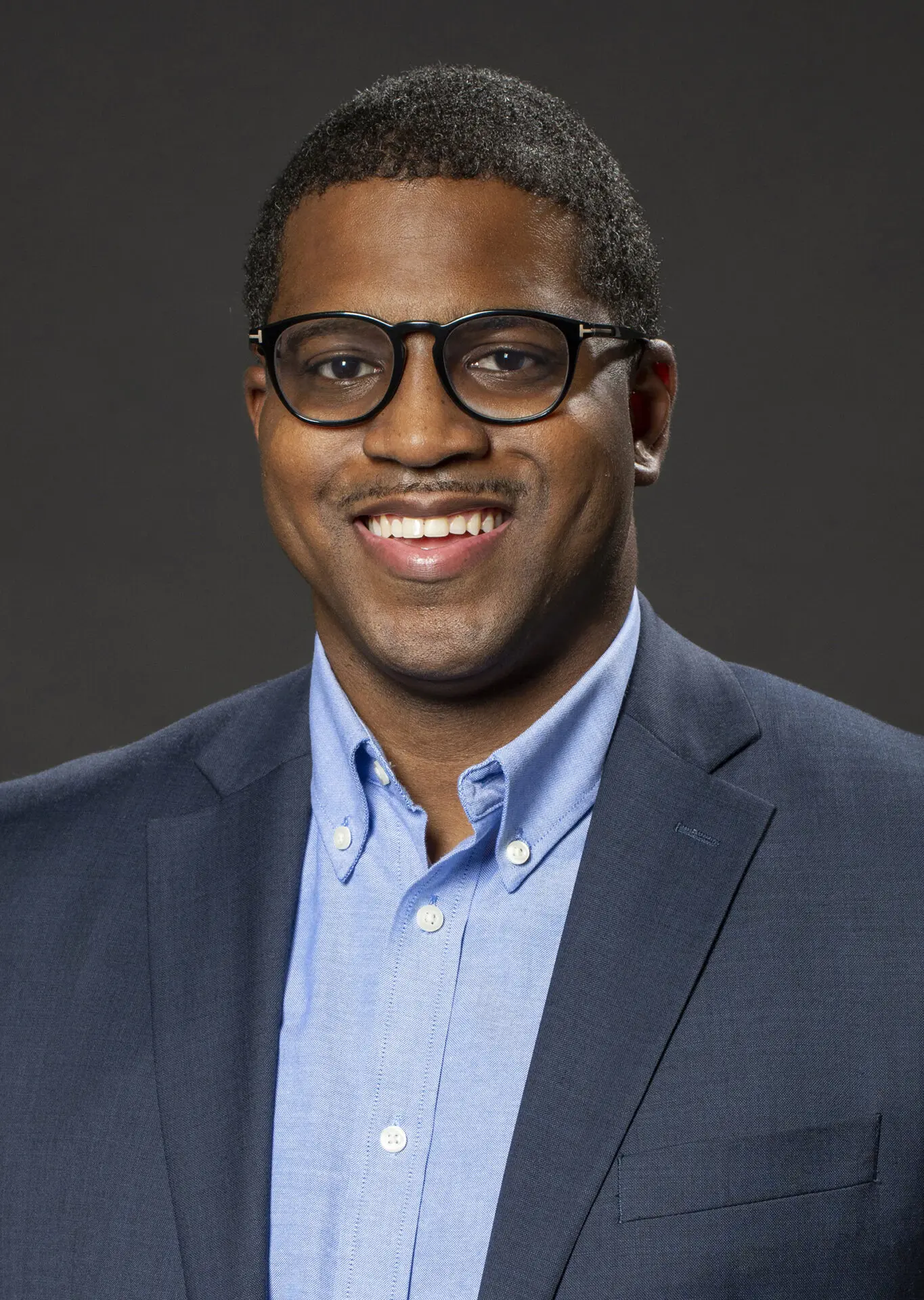 sutdio head shot of a Black man taken on a dark background.