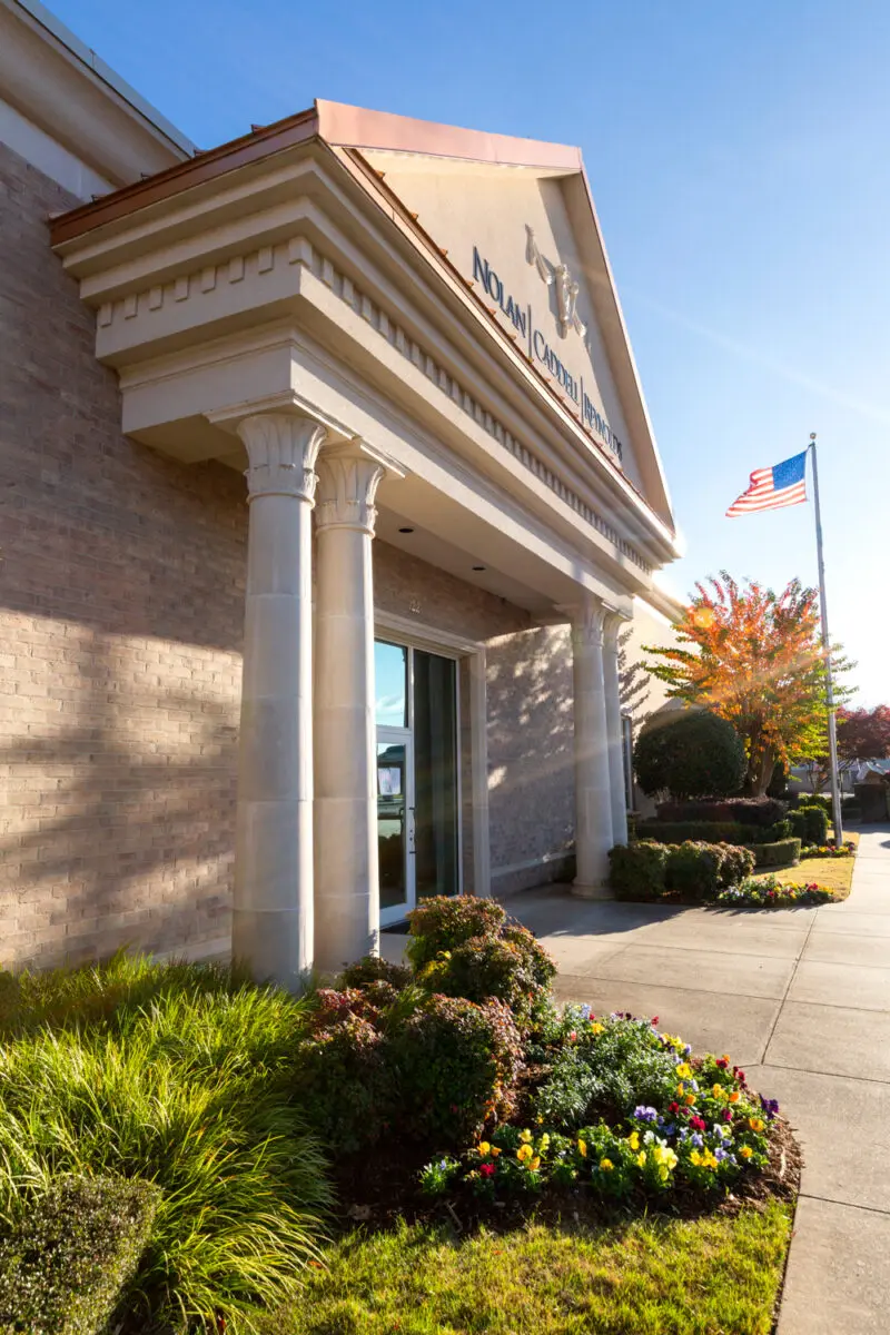 Exterior image of a building with yellow and orange trees planted nearby.