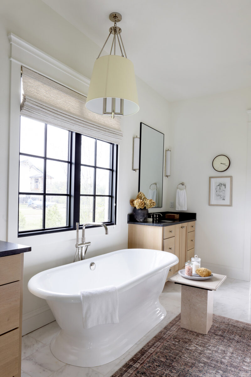 Large white bathtub in a primary bathroom with black countertops.