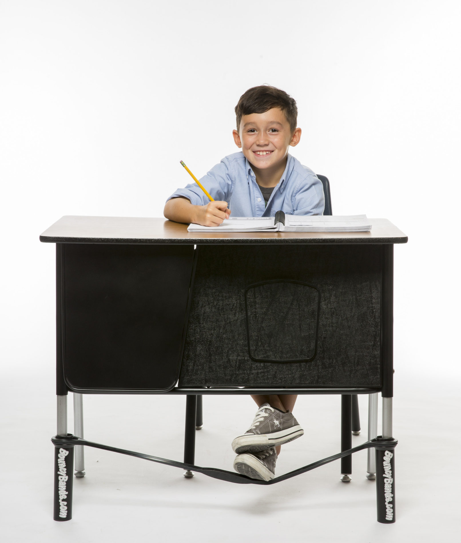 A child at a desk using a bouncy band.