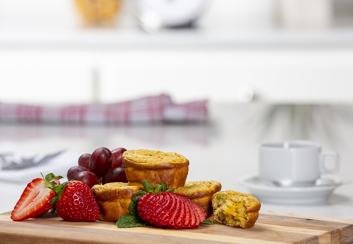 Photography of frittatas, strawberries and grapes on a wooden cutting board.