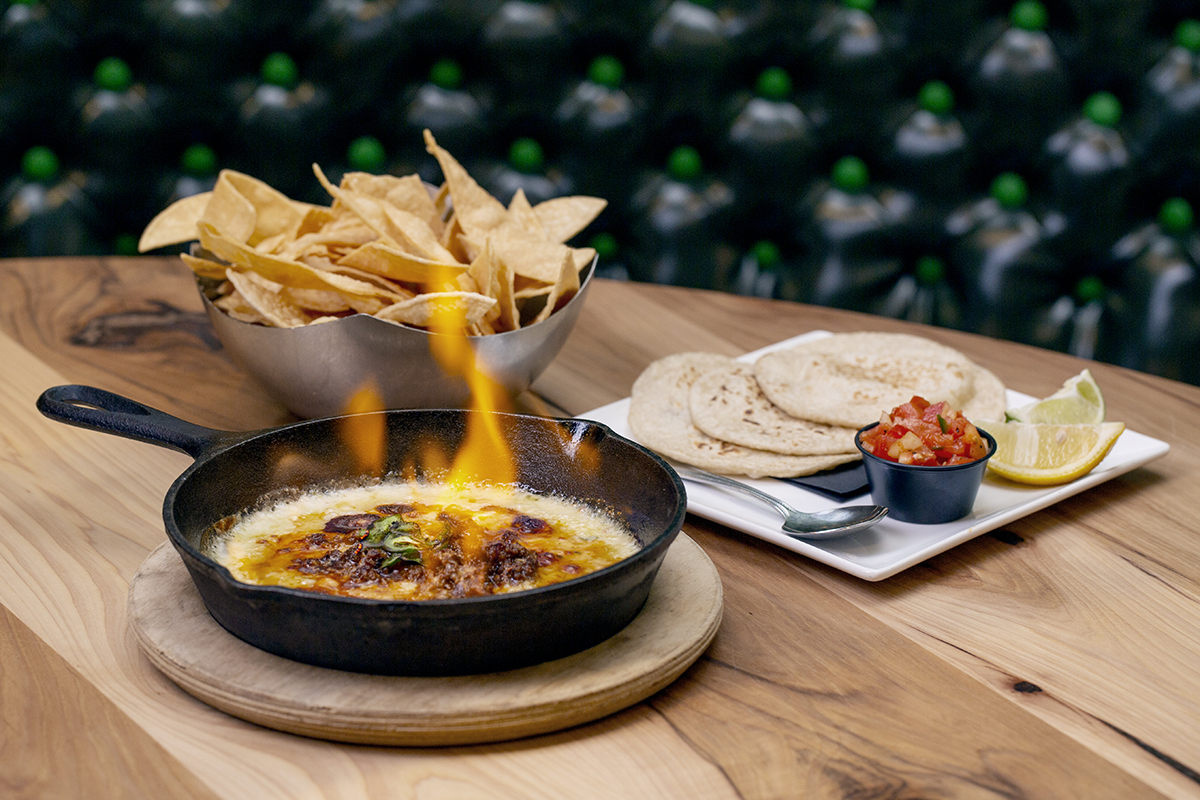 Photography of flaming queso, a basket of chips and fresh tortillas at a Local Lime restaurant