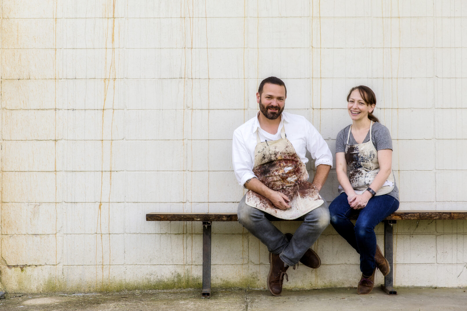 Portraits of two artists sitting on a bench outside their studio.