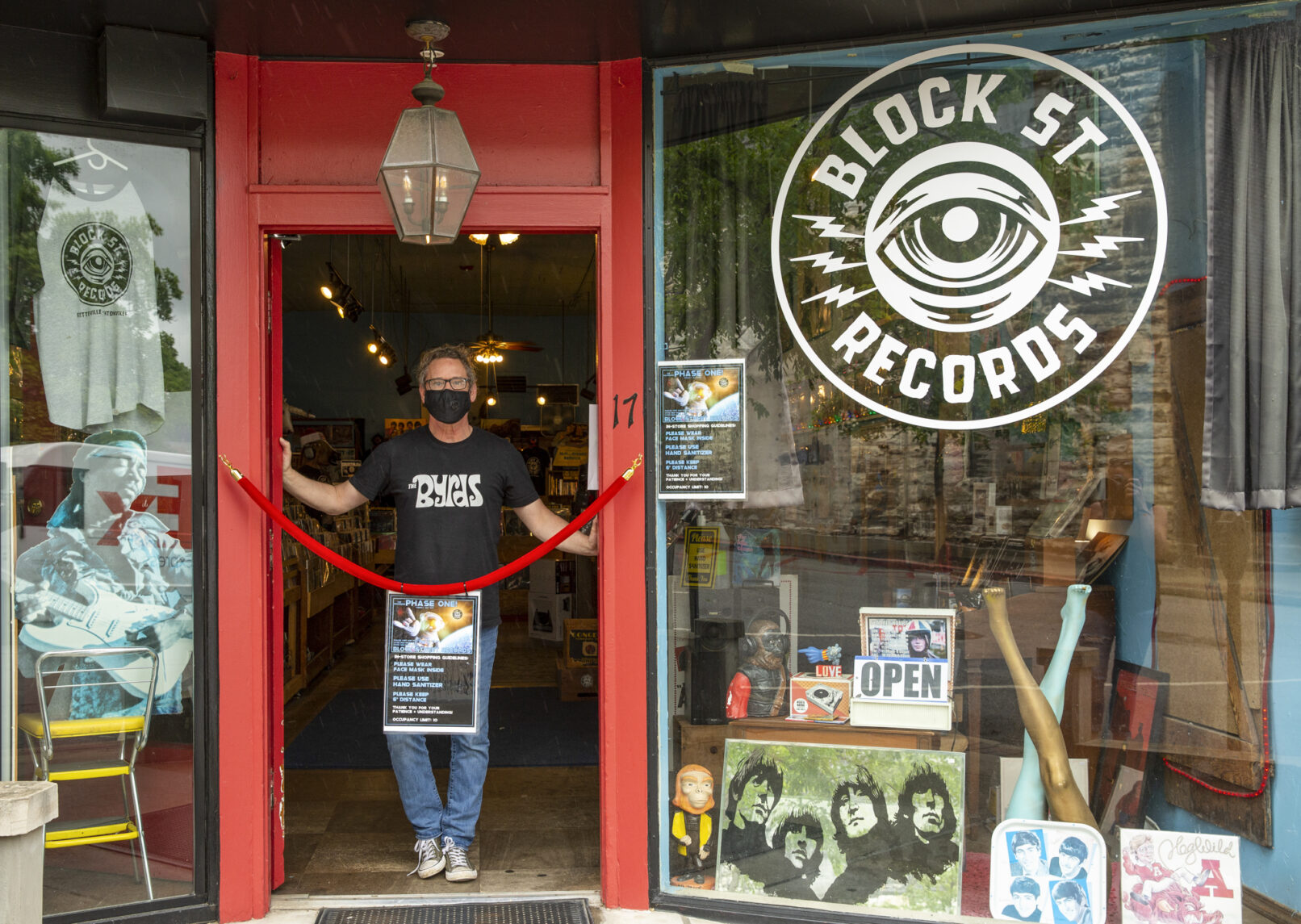 Portrait of a man standing in the doorway of his record business while wearing a mask for Covid in Fayetteville, Arkansas.