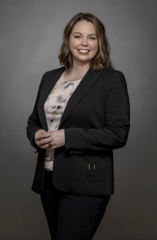 head shot of a woman taken in a photography studio on a gray background.