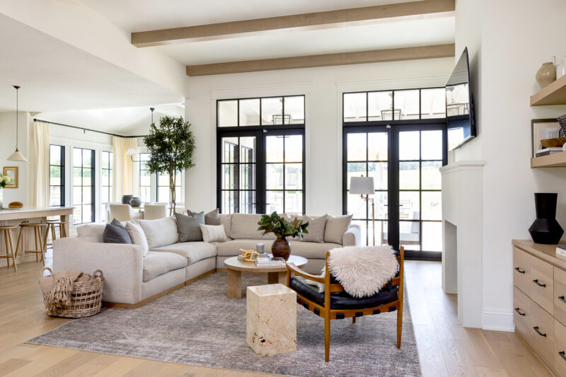 Interior photo of a living room decorated in neutral colors with a large l-shaped couch.