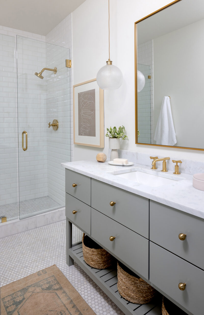 Interior photography of a bathroom with sage cabinets and white tile.