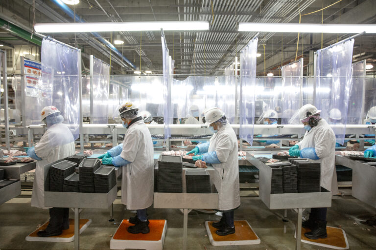 Employees of Tyson Foods, Inc., stand on a line in a meat packing plant in Tennessee.