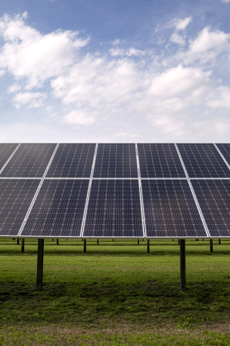 Solar Panels in a field against a cloudy, blue sky.