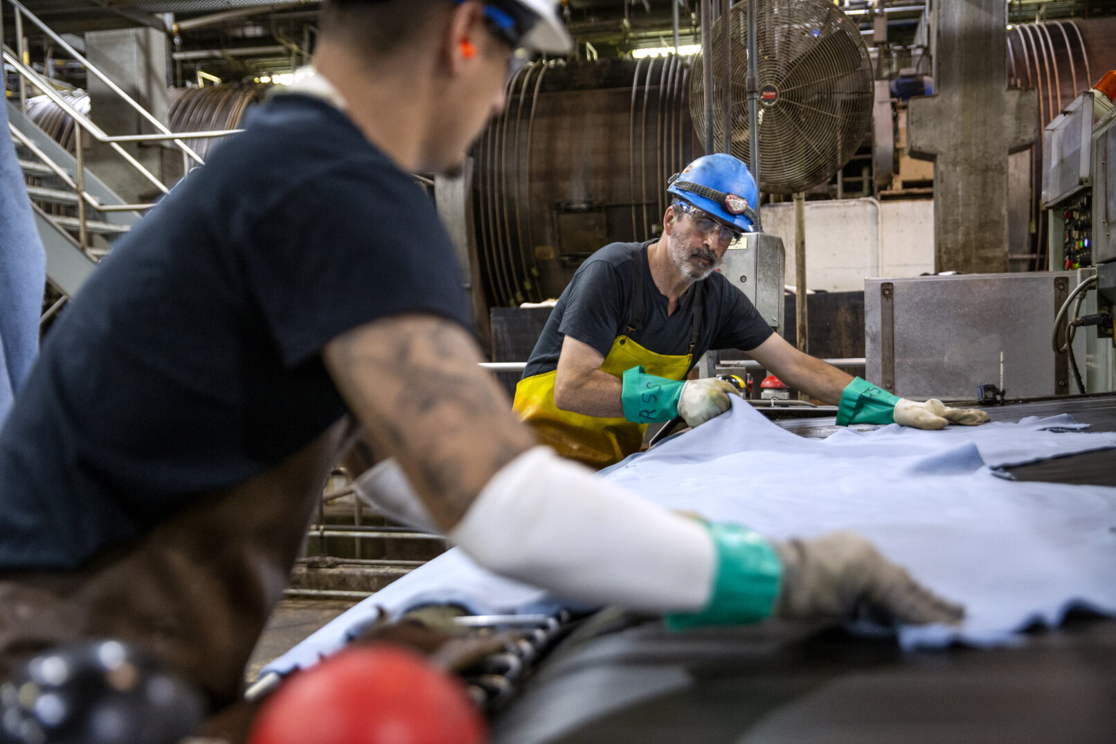 Two men work together to process leather at a tannery in South Dakota.