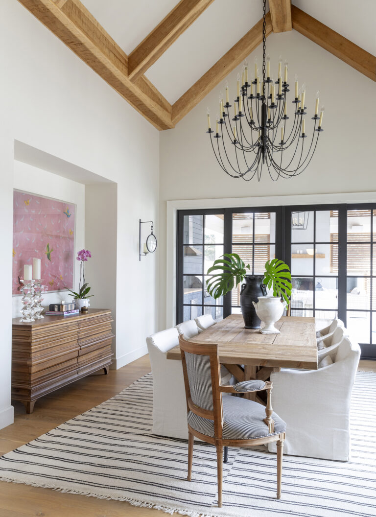 Photo of the interior of a dining room with a long table and wood beams on the ceiling.