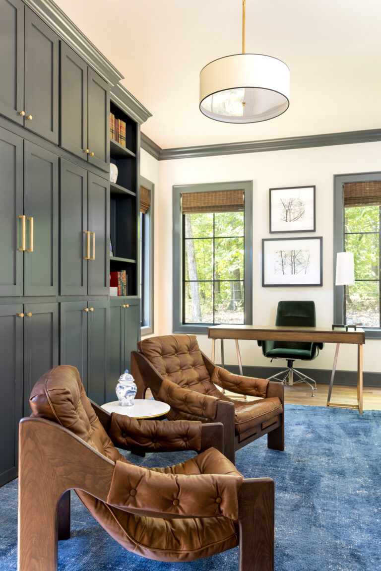 Photo of the interior of a den with a large dest and brown, leather chairs.