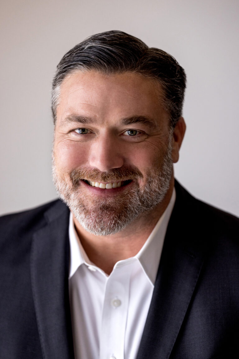 Studio headshot of a white man on a white background taken using natural lighting.