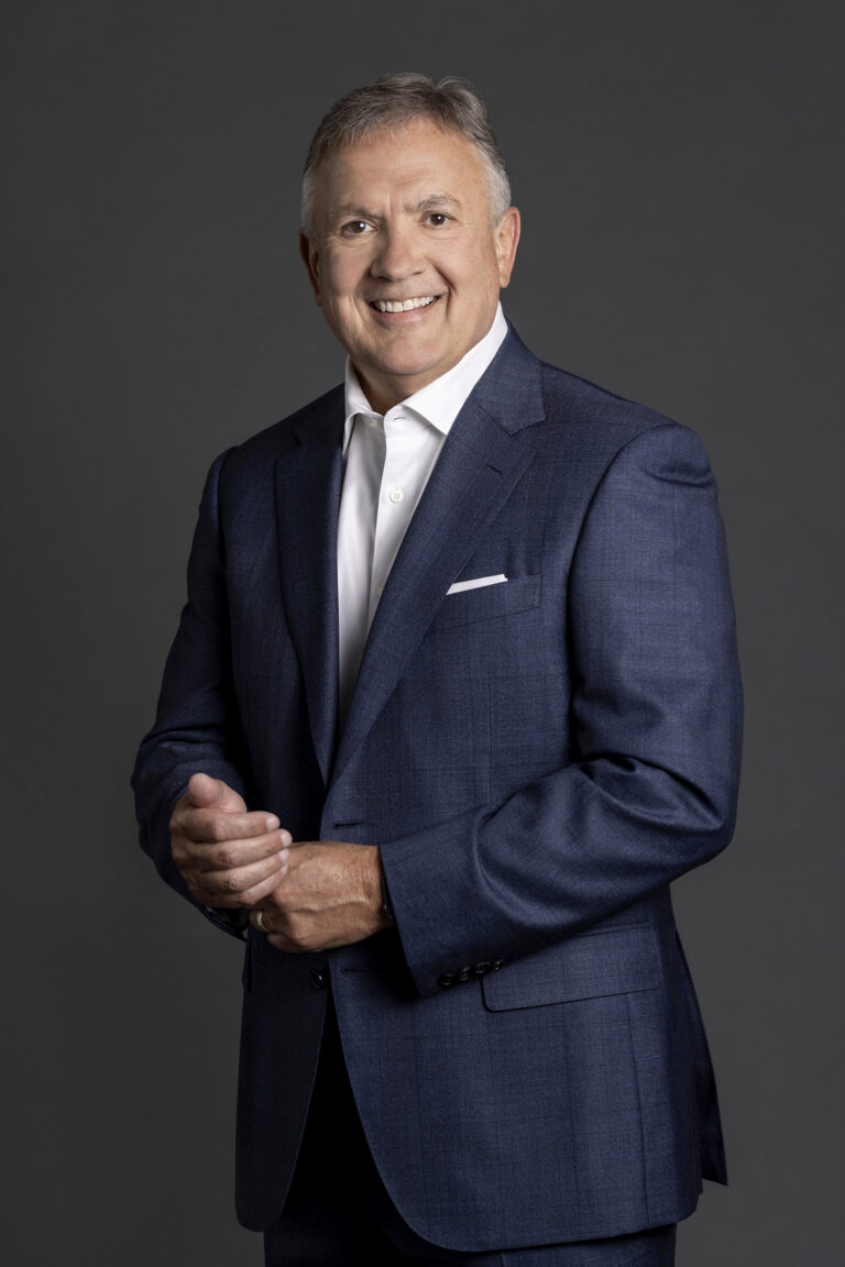 Studio portrait of a CEO on a dark gray background.