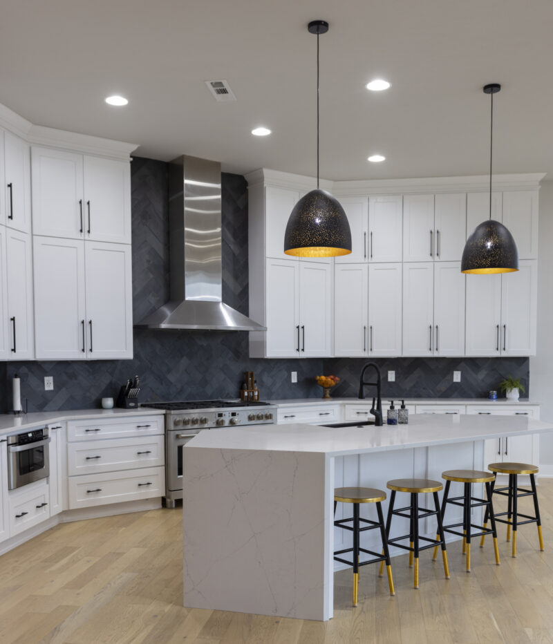 Interior of a white kitchen with black barstools.