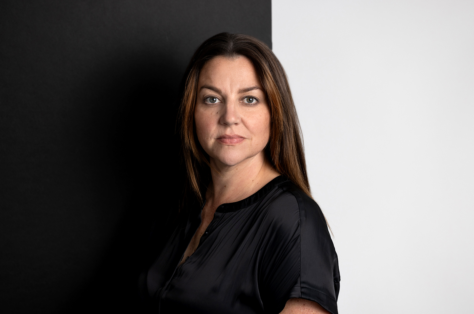 Studio portrait of a woman standing in front of a black and white background.