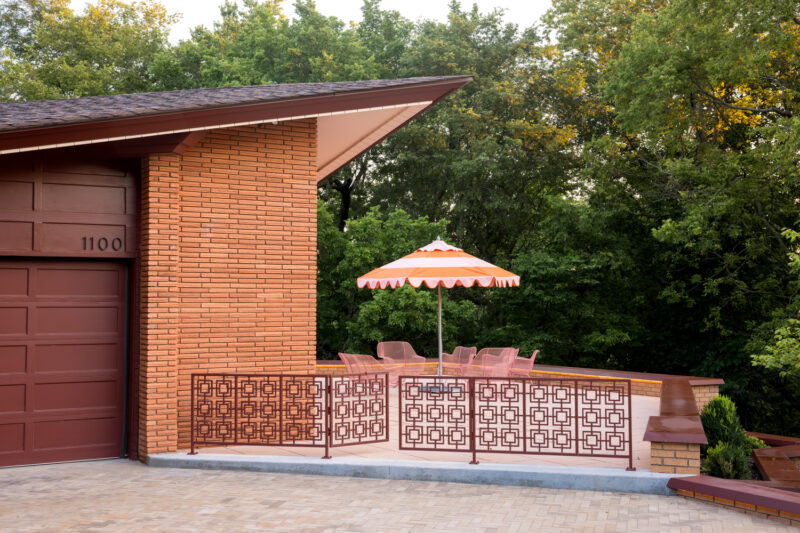 An entrance to the back porch of a red brick, mi-century modern home.