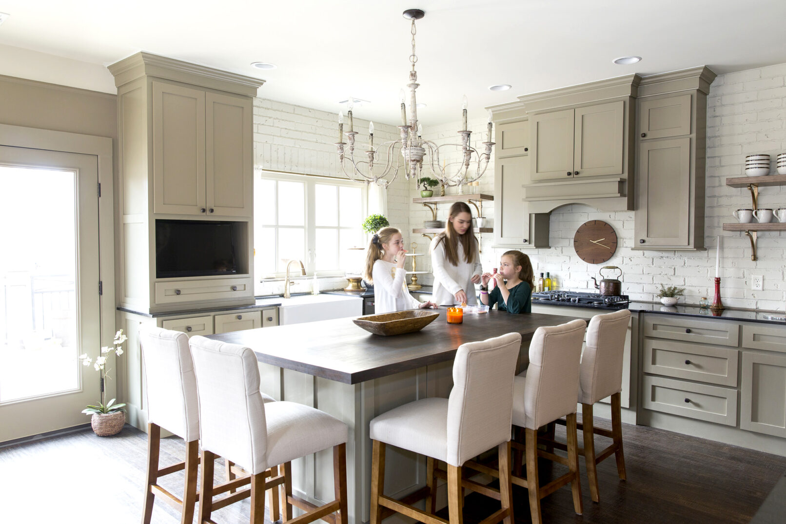 Children stand around a large kitchen island and snack during a photo shoot.