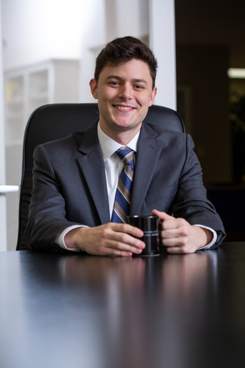 Portrait of a young attorney holding a coffee cup while sitting at a table.