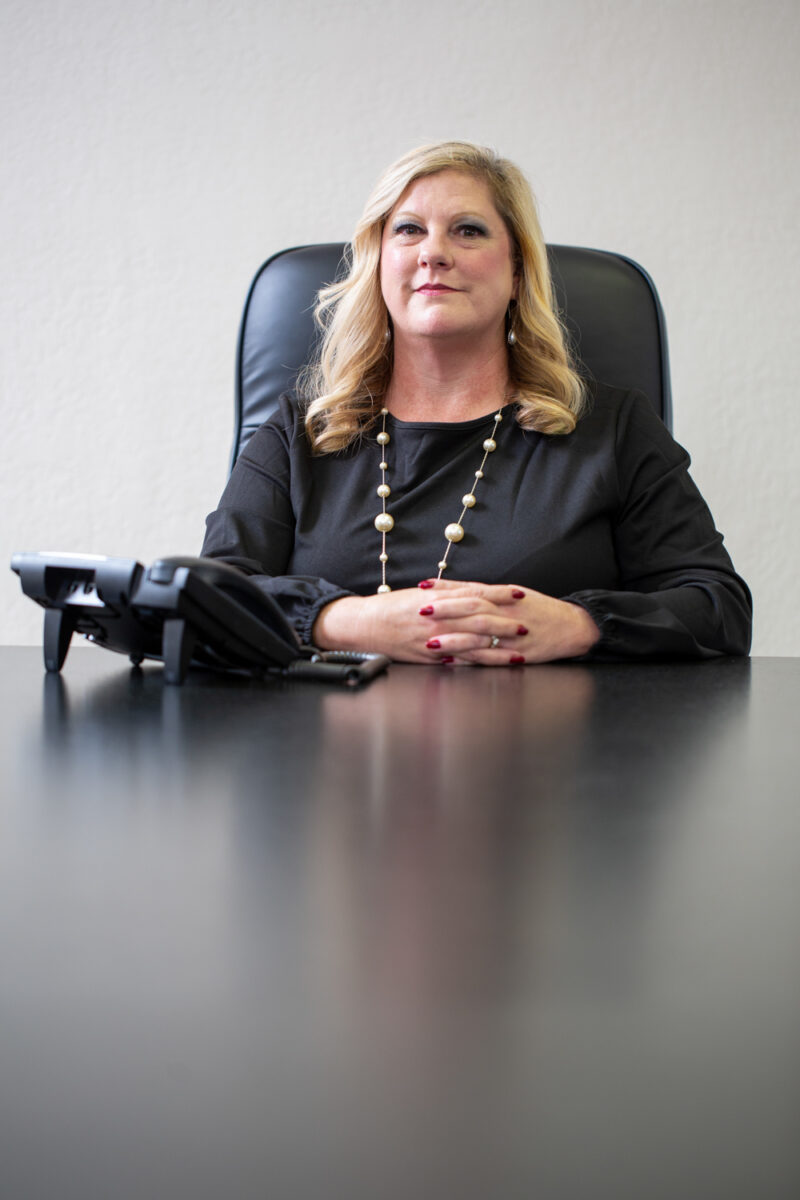 Portrait of anattorney holding near a phone while sitting at a table.