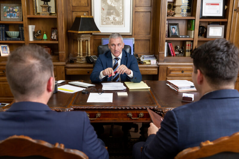 Group portrait of attorneys working while sitting at a desk.